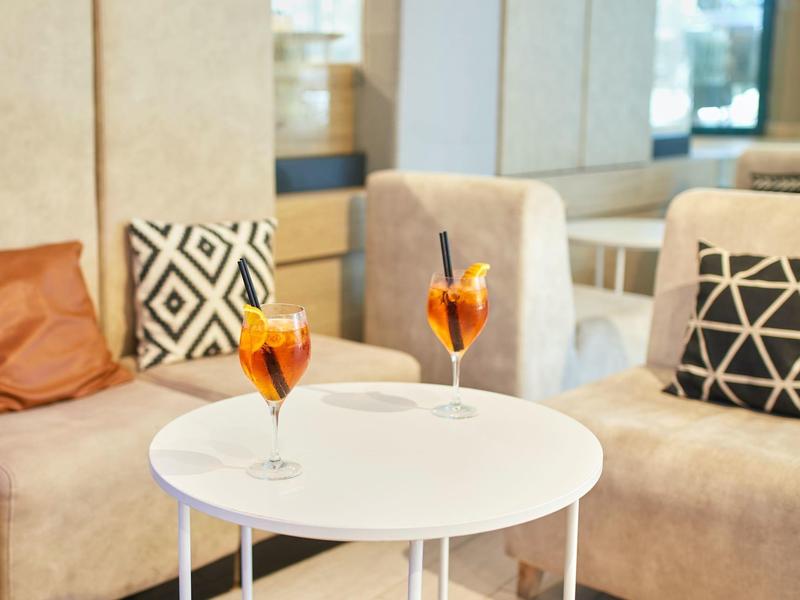 Dos cócteles naranjas sobre una mesa blanca redonda frente a sofás beige con cojines estampados.