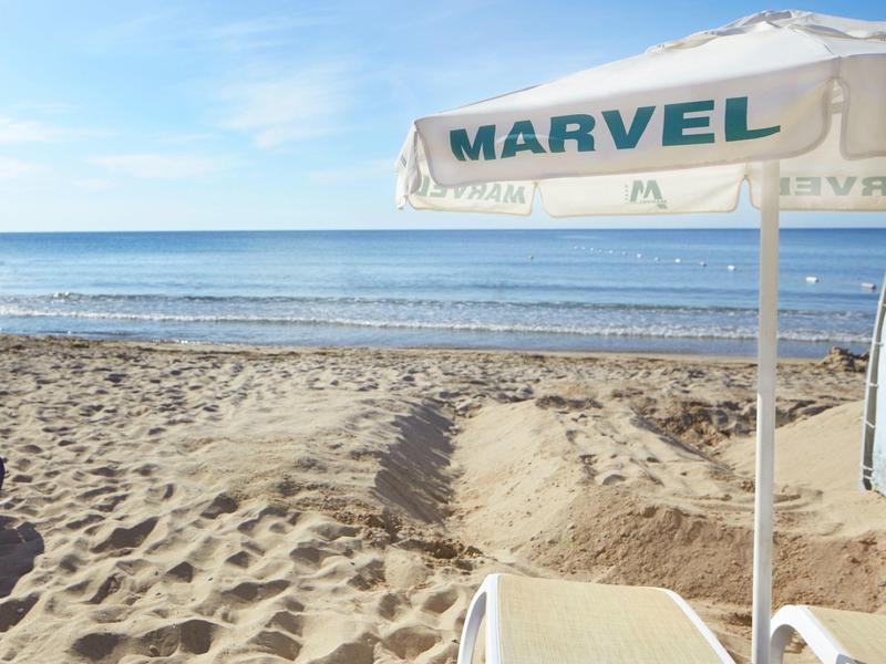 Vista de una playa arenosa con una sombrilla y el mar al fondo bajo un cielo despejado.