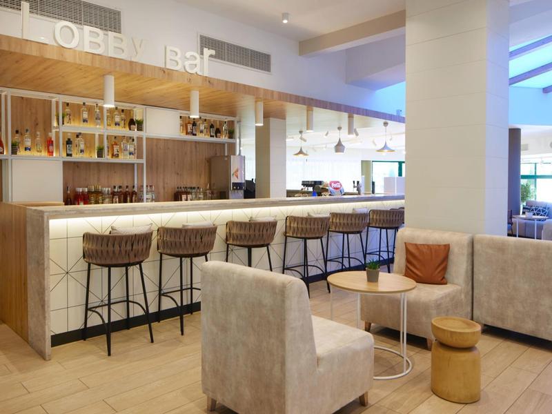 Moderna zona de bar de hotel con taburetes, asientos y ambiente acogedor.