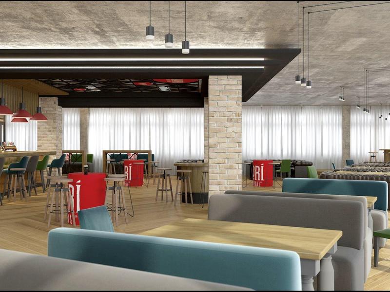 Área de lounge moderna en hotel con grupos de asientos, mesas y ventana grande con cortinas blancas.