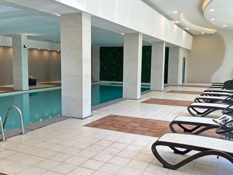 Zona de piscina cubierta con tumbonas y piscina en un entorno moderno de hotel