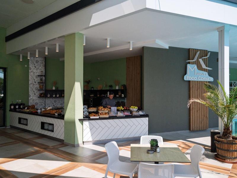 Luminosa recepción de hotel con mostrador moderno, zona de asientos y plantas verdes decorativas.