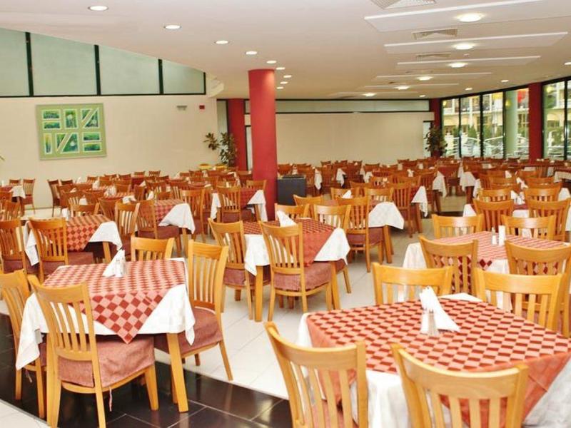 Amplio comedor con muchas mesas, sillas de madera y manteles a cuadros rojos y blancos.