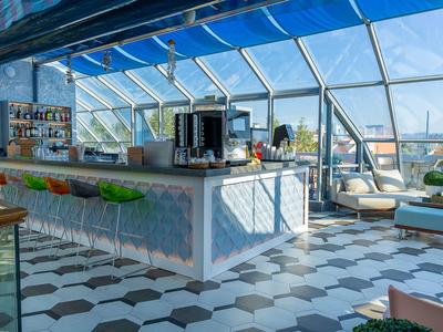 Světle osvětlený hotelový bar s moderním zařízením a panoramatickým výhledem skrz skleněné stěny.