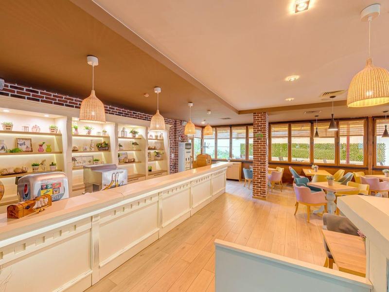 Heller, moderner Innenraum mit Holzdecke, weißen Theken, Regalen und großen Fenstern.