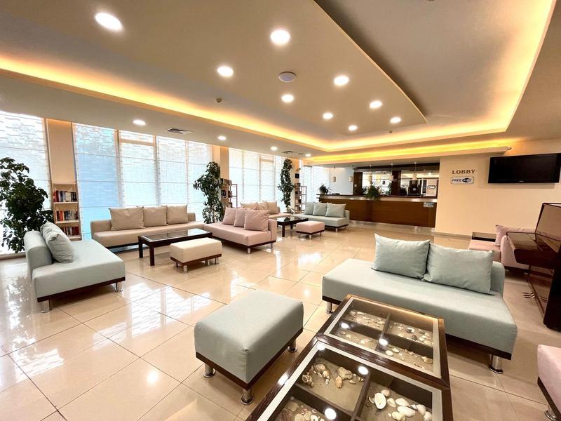 Heller, moderner Warteraum mit weißen Sofas, Glas-Couchtischen und warmem Deckenlicht.