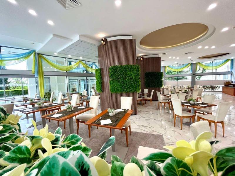 Helles Restaurant mit modernen Holzmöbeln und grünen Akzenten in einem Hotel.