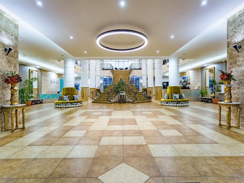 Großer Hotel-Lobby mit Marmorboden, Säulen, modernen Möbeln und rundem Deckengewölbe.