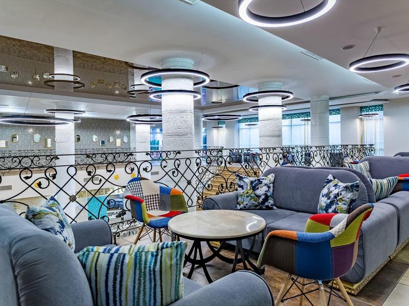 Moderner Loungebereich mit bunten Sofas, runden Tischen und verspielten Deckenlichtern.