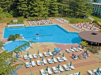 Grande piscina con lettini e ombrelloni in giardino di un hotel.