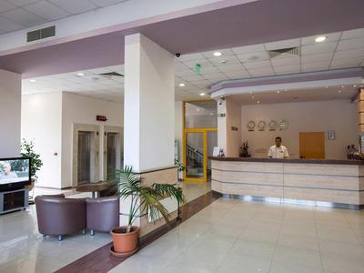 Area reception di un hotel moderno con banco, zona salotto e piante