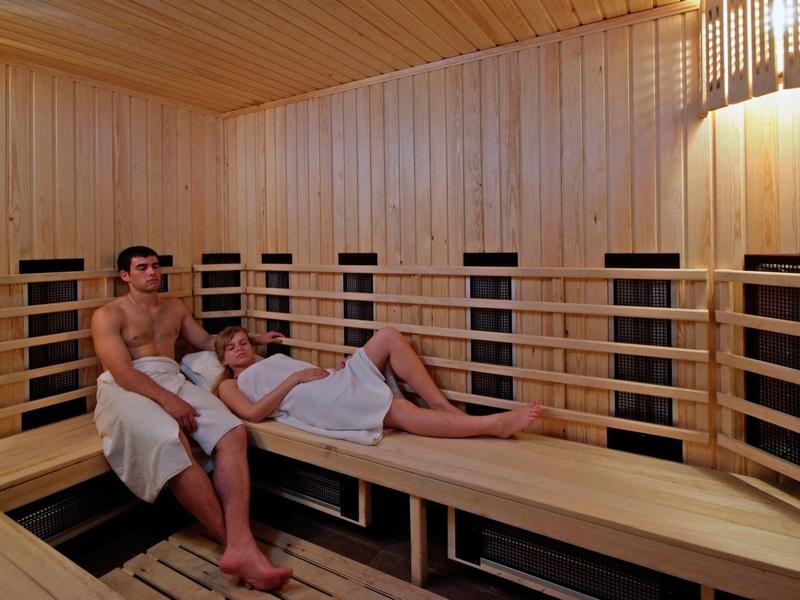 Drei Personen entspannen auf Holzbänken in einer finnischen Sauna mit Holzverkleidung.