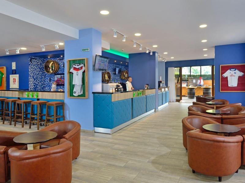 Heller und moderner Lounge-Bereich mit braunen Lederstühlen, blauen Wänden und Bartresen.