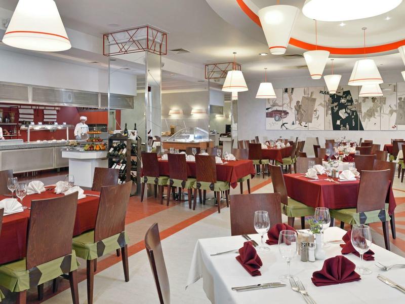 Modernes Hotelrestaurant mit rot bezogenen Stühlen und weiß gedeckten Tischen.