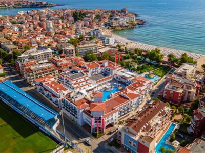 Luftaufnahme eines Küstenresorts mit Pool, Strand und umliegenden Gebäuden.