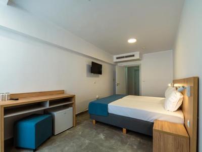 Modernes Hotelzimmer mit Doppelbett, Schreibtisch, Fernseher und Klimaanlage.