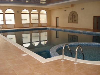 Hallenbad mit großen Fenstern und blau-weiß gekacheltem Whirlpool im Hotel.