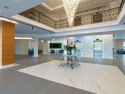 Heller Hotellobby mit Marmorboden, Blumen auf einem Tisch und dekorativen Geländern.