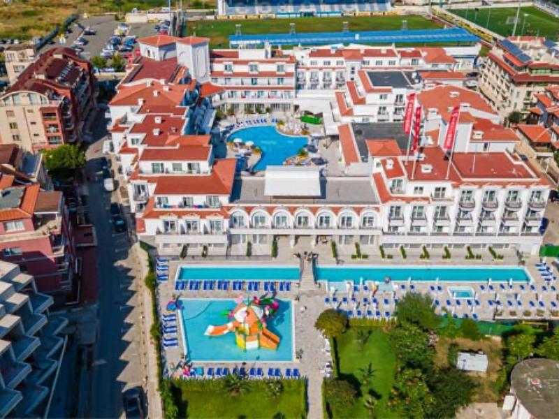 Luftaufnahme eines großen Resorts mit mehreren Schwimmbädern und roten Dächern an einem sonnigen Tag.