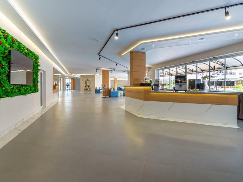 Moderner Hotellobby mit einer Rezeption, Sitzbereich und großem Fenster im Hintergrund.