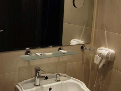 Moderne badkamer met witte wastafel, spiegel en wandgemonteerde haardroger.