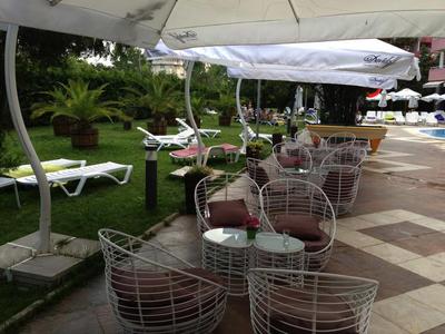 Sedie e tavoli in filo metallico sotto ombrelloni accanto a sdraio e prato