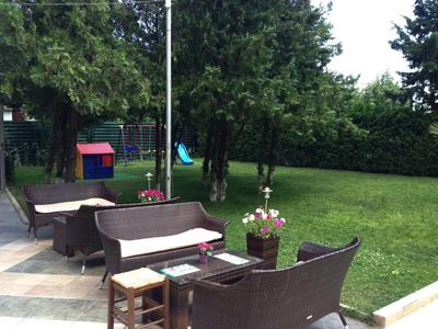 Zona salotto accogliente con mobili imbottiti marroni e tavolo in legno nel giardino verde di un hotel.