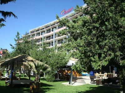 Area verde dell'hotel con palme, sedie a sdraio e un edificio a più piani sullo sfondo