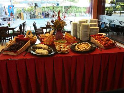 Tavolo buffet con assortimento di dolci e pasticcini decorati con fiori in un'area ristorante luminosa.