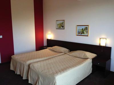 Twee eenpersoonsbedden met crèmekleurige dekens in een eenvoudige hotelkamer met donkere meubels.