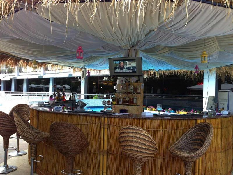 Gezellige bar met hoge stoelen en een met stro bedekt toonbank in tropische stijl.