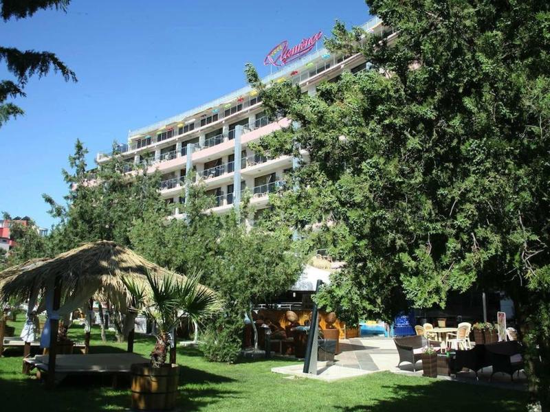 Hotelgebouw met meerdere verdiepingen, omgeven door bomen en een tuin met zitgedeeltes.