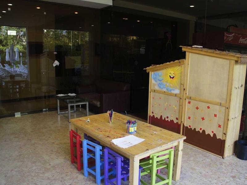 Kleurrijke kinderstoel en tafel in een binnenruimte van een hotel naast een gesloten receptie.