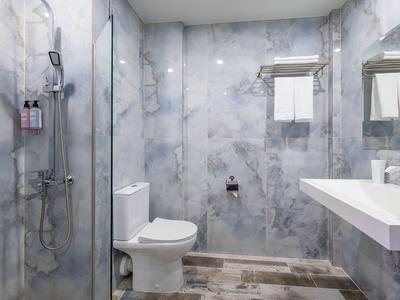 Moderne badkamer met glazen douche, wit toilet en grote spiegel.