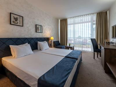 Modern hotelkamer met twee eenpersoonsbedden, bureau en groot raam met uitzicht.