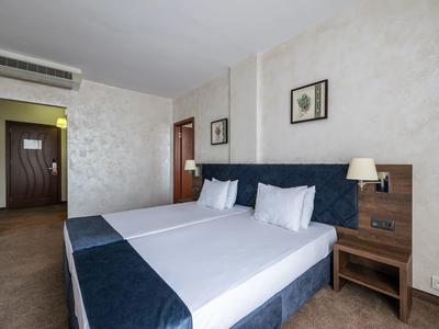 Licht ingerichte hotelkamer met twee eenpersoonsbedden en nachtkastjes.