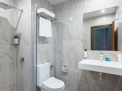 Moderne badkamer met marmeren tegels, toilet, wastafel en inloopdouche.