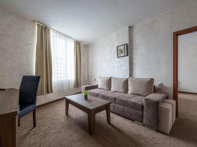 Licht gemeubileerde woonkamer met bank, salontafel en groot raam in een hotelkamer.