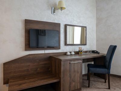 Moderne werkplek in hotelkamer met houten bureau, stoel en wand-tv.