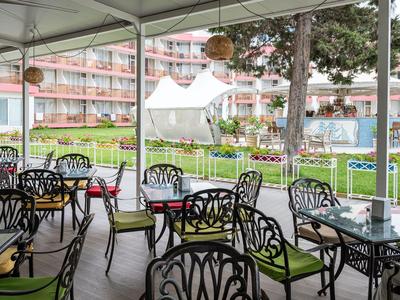 Overdekt terras met decoratieve stoelen en tafels voor een hotelgebouw.