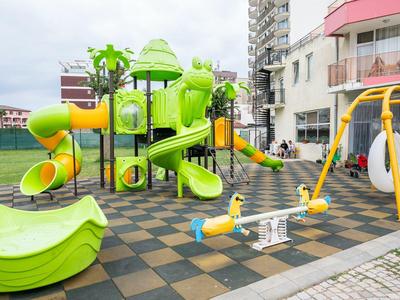 Kleurrijke speeltuin met glijbanen, schommels en wip voor woongebouwen.