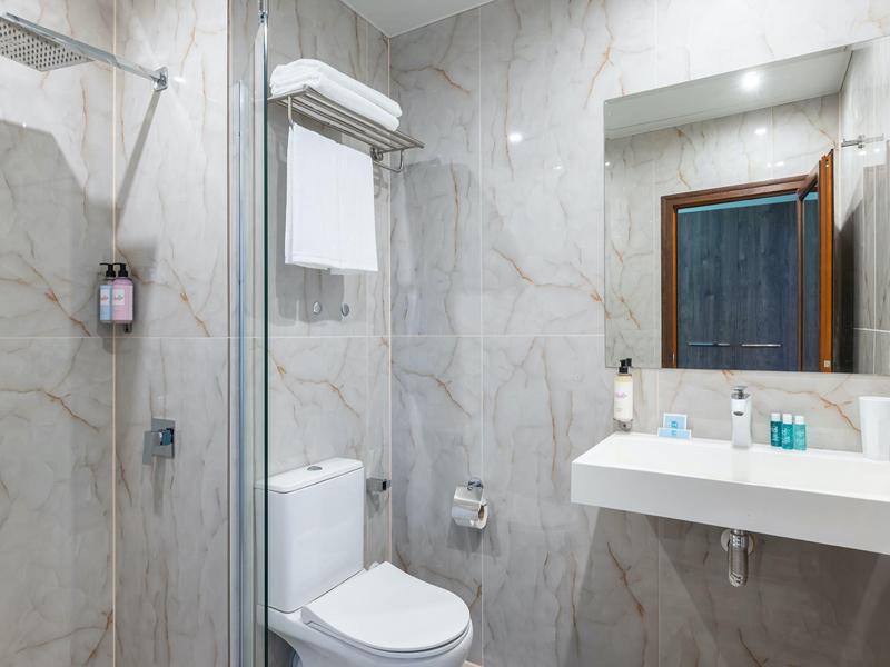 Moderne badkamer met marmeren tegels, toilet, wastafel en inloopdouche.