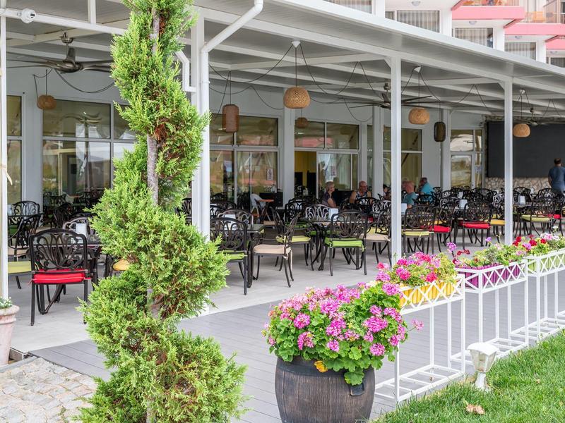 Buitengebied van restaurant met tafels, stoelen en bloemdecoraties.