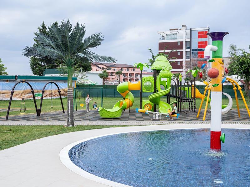 Kinderspeelplaats met glijbanen en watergebied in een vakantiepark.