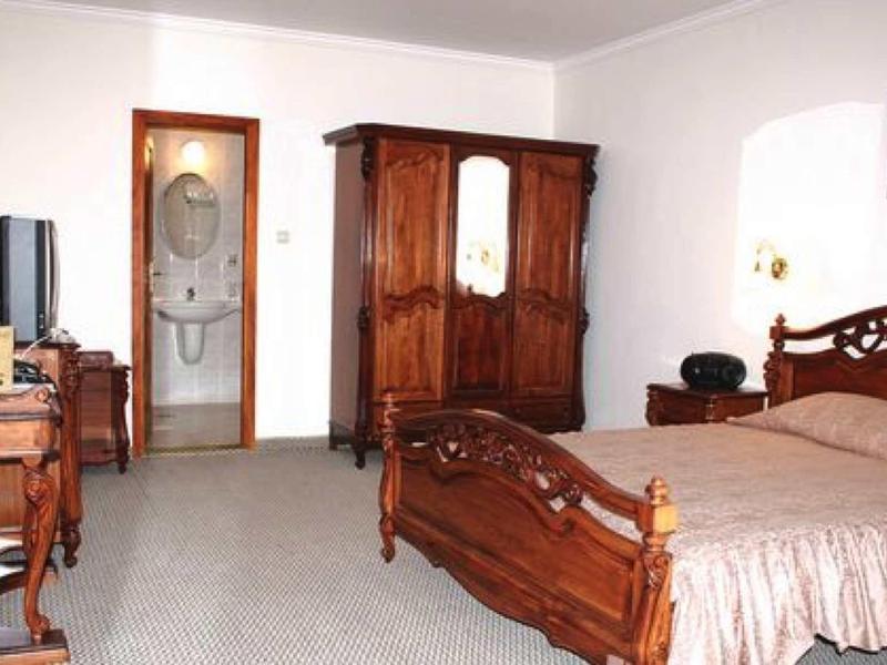 Slaapkamer met houten meubels en open badkamer met toilet en wastafel