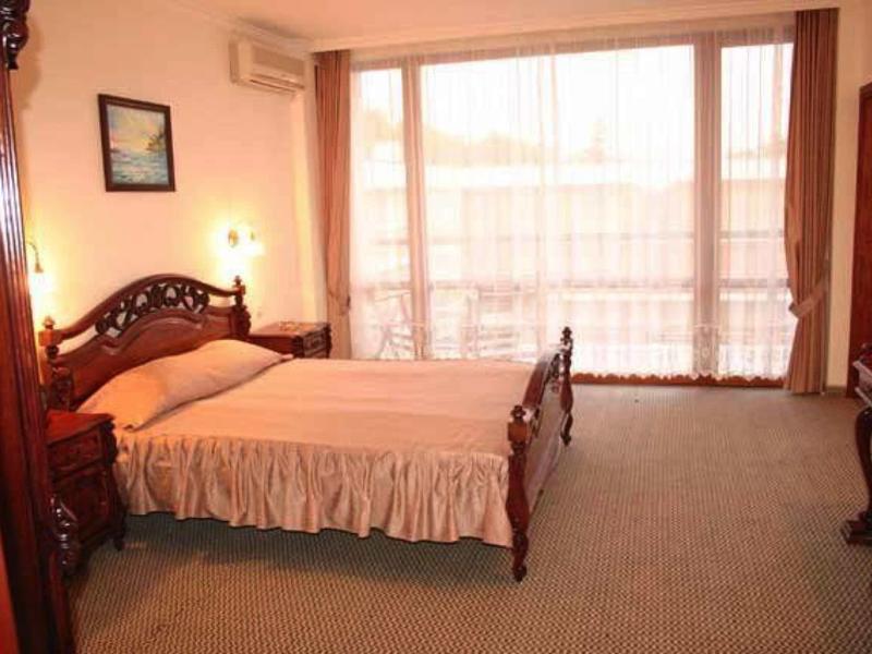 Lichte hotelkamer met tweepersoonsbed, balkon en tapijtvloer.