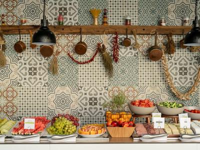 Buffet mit Obst, Gemüse und Gewürzen vor einer bunten Tapetenwand im rustikalen Stil.