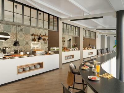 Moderner Frühstücksbereich mit Buffet und Sitzgelegenheiten in einem Hotel.