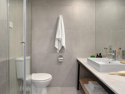 Modernes Badezimmer mit Toilette, Waschbecken auf einer langen Arbeitsplatte und Handtüchern.