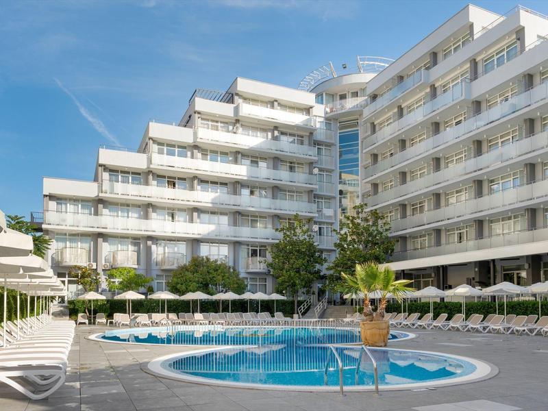 Moderner Hotelkomplex mit Pool, Sonnenliegen und blauen Himmel im Hintergrund